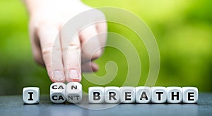 Hand turns dice and changes the expression `I can`t breathe` to `I can breathe`.