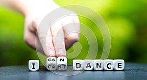 Hand turns dice and changes the expression `I can`t dance` to `I can dance`.