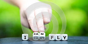 Hand turns dice and changes the expression `I can`t fly` to `I can fly`.