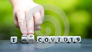 Hand turns dice and changes the expression `I have covid 19` to `I had covid 19`.