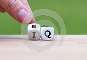 Hand turns a dice and changes the expression `IQ` Intelligence Quotient to `EQ` Emotional Intelligence/Quotient`.