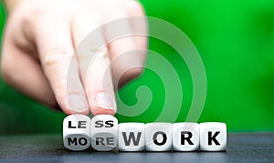 Hand turns dice and changes the expression `more work` to `less work`.
