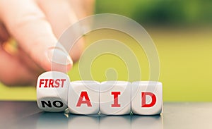Hand turns a dice and changes the expression `no aid` to `first aid`.