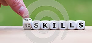 Hand turns a dice and changes the expression `no skills` to `top skills`. photo