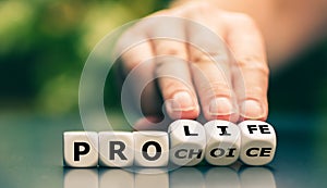 Hand turns dice and changes the expression `pro choice` to `pro life`. photo