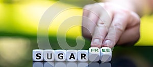 Hand turns dice and changes the expression `sugar` to `sugar free`.