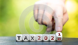 Hand turns dice and changes the expression `tax 2020` to `tax2021`.