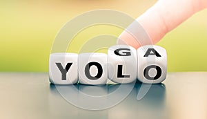 Hand turns dice and changes the expression `yolo` to `yoga`, or vice versa. photo