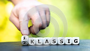 Hand turns dice and changes the German expression `2. klassig` second class to `1. klassig` first class. photo