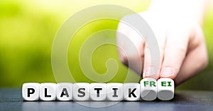 Hand turns dice and changes the German expression `plastik` plastic to `plastik frei` plastic free.