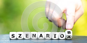 Hand turns dice and changes the German expression `szenario A` scenario A to `szenario B` scenario B.