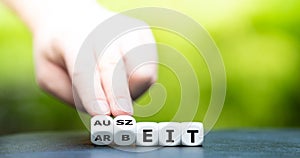 Hand turns dice and changes the German word `Arbeit` work to `Auszeit` time off.