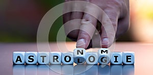 Hand turns dice and changes the German word `Astrologie` `Astrology` to `Astronomie` `Astronomy`.