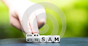 Hand turns dice and changes the German word `einsam` lonesome to `zweisam` twosome.