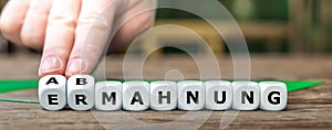 Hand turns dice and changes the German word 'Ermahnung' to 'Abmahnung' .