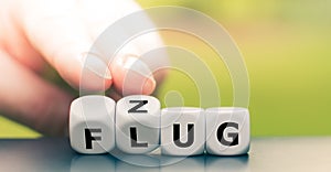 Hand turns dice and changes the German word `Flug` `flight` in English to `Zug` `train` in English`.