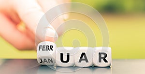 Hand turns a dice and changes the German word `Januar` `January` in English to `Februar` `February` in English.