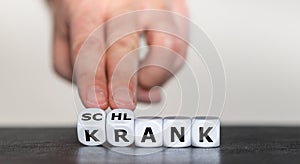 Hand turns dice and changes the German word `krank` sick to `schlank` slim. photo
