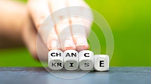 Hand turns dice and changes the German word `Krise` crisis to `Chance` chance.