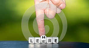 Hand turns dice and changes the German word `Leere` emptiness to `Lehre` education. photo