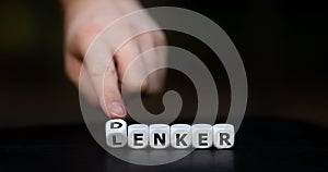 Hand turns dice and changes the German word `Lenker` guide to `Denker` thinker.