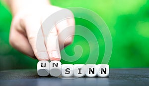 Hand turns dice and changes the German word `Sinn` sense to `unsinn` nonsense.