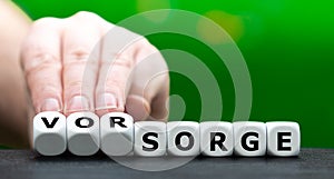 Hand turns dice and changes the German word `Sorge` worries to `Vorsorge` medical check up photo