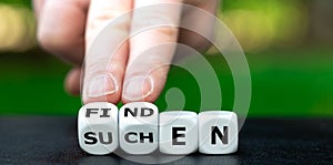 Hand turns dice and changes the German word `suchen` search to `finden` find. photo