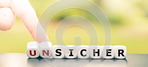 Hand turns dice and changes the German word `unsicher` `unsafe` to `sicher` `safe`.