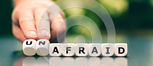 Hand turns dice and changes the word `afraid` to `unafraid`.