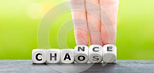 Hand turns dice and changes the word chaos to chance