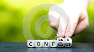 Hand turns dice and changes the word `conflict` to `confess`.