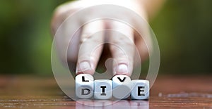 Hand turns dice and changes the word die to live.