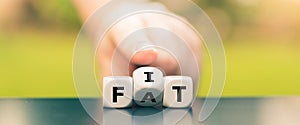 Hand turns dice and changes the word `fat` to `fit`.
