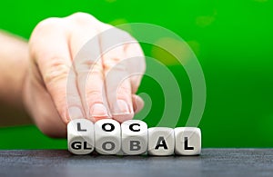 Hand turns dice and changes the word global to local.