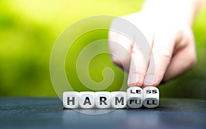 Hand turns dice and changes the word `harmful` to `harmless`.