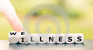 Hand turns dice and changes the word `illness` to `wellness`.