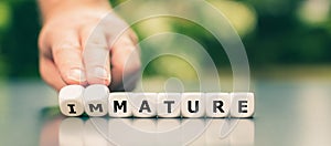 Hand turns dice and changes the word `immature` to `mature`.