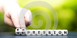 Hand turns dice and changes the word `impression` to `expression`.