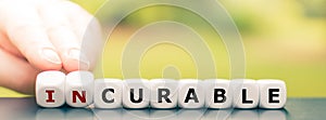 Hand turns dice and changes the word `incurable` to `curable`. photo