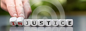 Hand turns dice and changes the word `injustice` to `justice`.