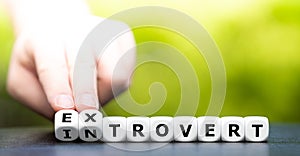 Hand turns dice and changes the word introvert to extrovert