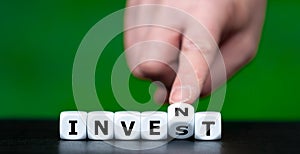 Hand turns dice and changes the word invest to invent