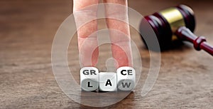 Hand turns dice and changes the word law to grace.