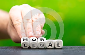 Hand turns dice and changes the word `legal` to `moral`.