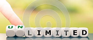 Hand turns dice and changes the word `limited` to `unlimited`. photo