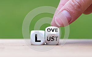 Hand turns a dice and changes the word `lust` to `love`, or vice versa. photo