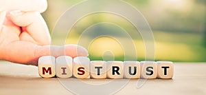 Hand turns dice and changes the word `mistrust` to `trust`. photo