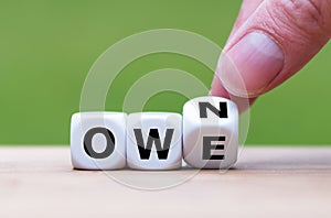 Hand turns a dice and changes the word `owe` to `own`.