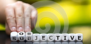 Hand turns dice and changes the word `subjective` to `objective`. photo